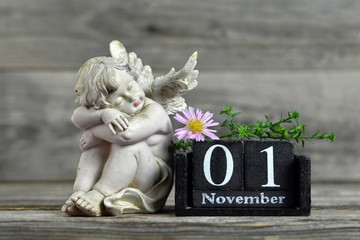 All Saints Day. Angel, wooden calendar and flower