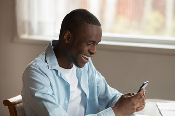 Overjoyed biracial man feel euphoric texting on smartphone