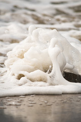 Fototapeta na wymiar Close-up of Foamy Water Rolling onto Shore