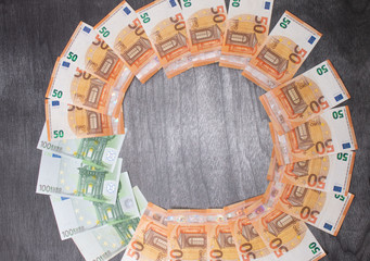 Euro banknotes Laid out in a cicircle on a grey wooden background. Money finance earning sector concept. Copy space for text. Stack of money wealth, lottery prizes or banking crises.
