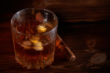 glass of whiskey with cigar on a wooden table
