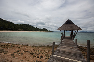 a view to the shore of Koh Talu with a trditional boat on a cloudy day, Thailand