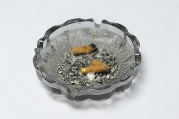 glass ashtray with ash and cigarette butts on white background