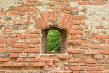 Arched window in the ancient red brick wall.