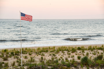 Fototapeta premium US flag flying over Dewey Beach at sunset