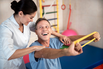 Obraz premium Happy man doing exercises with rubber band for fitness