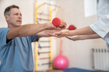 Male patient is making complex exercises in hospital