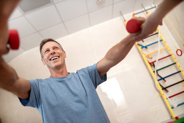 Obraz premium Happy patient is doing exercises with dumbbells