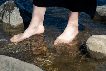 Close up of woman's legs standing in the lake. Back to Nature concept. Vacation and Relaxation.