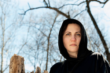 Hooded Woman in black robes deep in the Forest. Witches. Halloween and Gothic concept. Witchcraft and magic. Scary. 