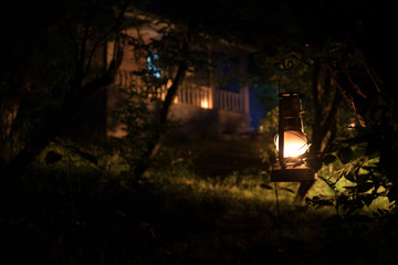 Horror Halloween concept. Burning old oil lamp in forest at night. Night scenery of a nightmare scene.