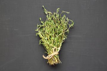 Raw organic fresh thyme on a black surface, side view. Close-up.