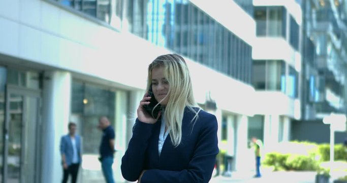 Blonde business woman talking on the mobile phone in modern office complex environment