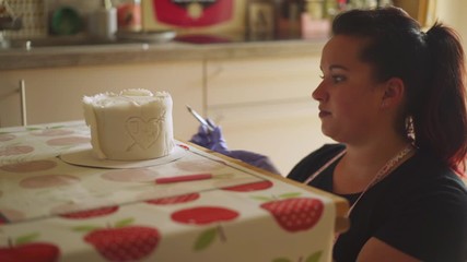 Celebration cake making, worker decorating icing detail, closeup