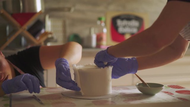 Celebration cake making, workers decorating fondant icing on candle cake
