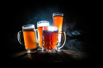 Creative concept. Beer glasses on wooden table at dark toned foggy background.