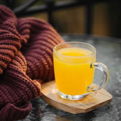 Hot sea buckthorn tea in  glass  with warm sweater. Traditional Autumn Drink