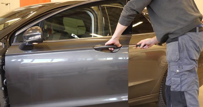 Skilled automobile body technician quickly removes a car door handle with a screwdriver - static