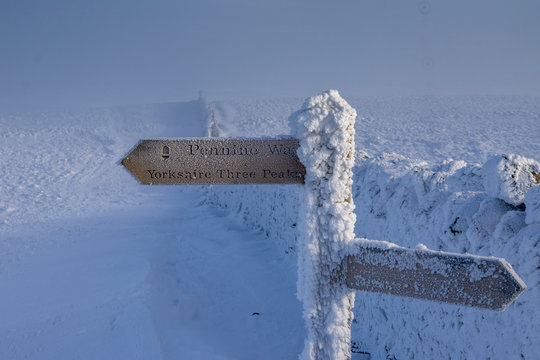 At the summit of Penyghent part of the yorkshire three peaks, a pennine way sign covered in snow