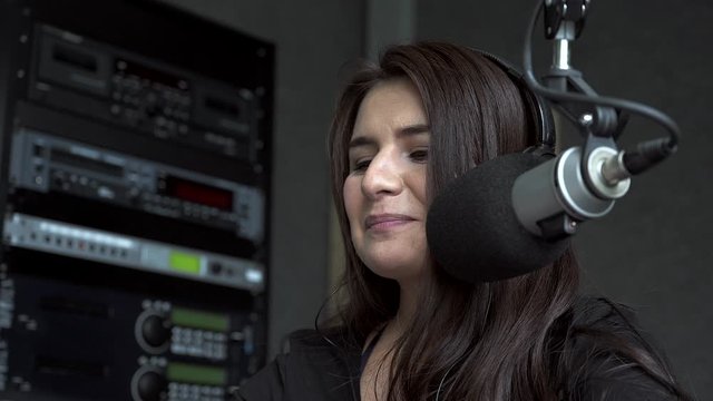 close up shot of young female radio host speaking into the microphone with a smille on her face