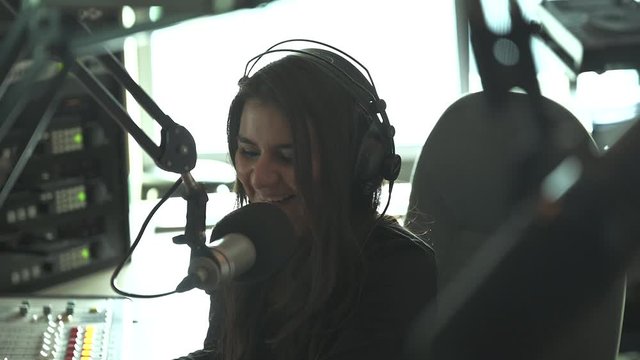close up shot of young female radio host speaking into the microphone with a smille on her face