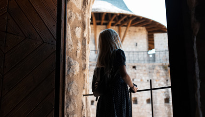 Back view of young girl with backpack who travel in fortress.
