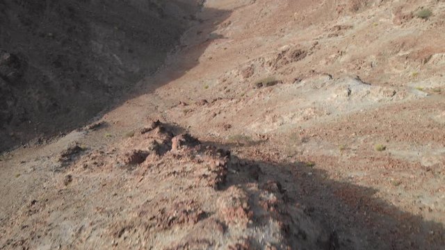 Revealing aerial epic shot from drone of an young male standing on top of a rocky mountain in Hatta, United Arab Emirates