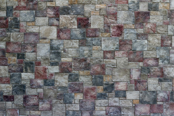 Colorful modern marble-like tile wall texture with blocks in varying hues of rose red, blue, and gray