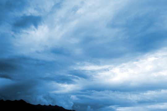 Abstrakter Hintergrund - blaue Wolken mit dunklen Bergkamm