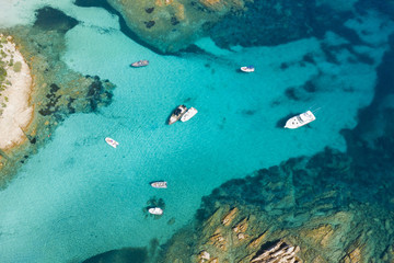 View from above, stunning aerial view of some boats and luxury yachts floating on a turquoise water. Maddalena Archipelago National Park, Sardinia, Italy.