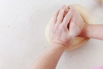 Fototapeta premium Hands chef knead dough for pizza. Knead dough with your hands. Woman's hands knead dough. Cooking pizza.