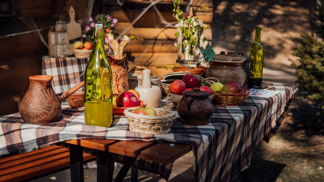 A laid table in a rustic style on the street. An exhibition of rustic interior. rural still life table. Still life with ripe apples and a bottle of moonshine