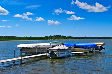 Boat dock with raised pontoons on beautiful lake in northern Minnesota with blue sky and fluffy...