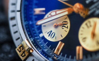 Macro detail of luxury blue fashion watch with gold color arrows. Close up of a watches