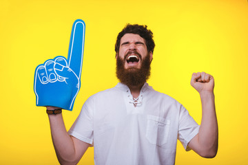 Photo of screaming supporter, with big blue finger glove, over yellow background