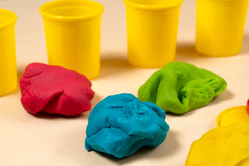 Green, blue, yellow and red play dough on wooden table