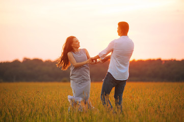 Fototapeta premium Photo of couple dancing in a file on sunset, having fun