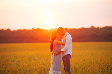 Sunset lights, couple, embracing in a field, and looking  in each other eyes