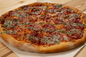 Salami pizza with basil sauce on wooden background - Close up
