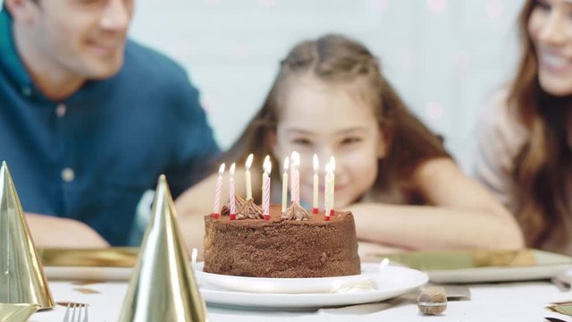 Closeup smiling birthday girl blowing 12 birthday candles in luxury house.