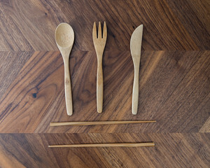 Reusable environmentally friendly bamboo travel utensils on a wooden background arranged into a pattern