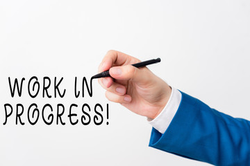 Text sign showing Work In Progress. Business photo showcasing unfinished project that still added to or developed Isolated hand above white background. Pointing pen in the hand on white background