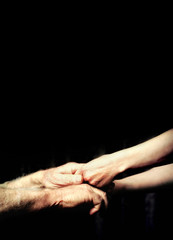 close up senior adult male hand and young adult female hand holding each other