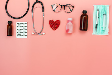 Table top view aerial image of accessories healthcare & medical background concept.Red heart & stethoscope with essential objects on pink paper.Flat lay of idea for doctor treat patient in hospital.