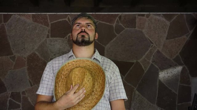 A man with a straw hat is sad. Mourns for the departed. On the face is a beard. Portrait to the waist. 4K video
