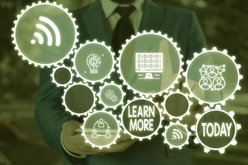 Text sign showing Learn More. Business photo text knowledge or skill acquired by instruction Considerable learning Male human wear formal work suit presenting presentation using smart device
