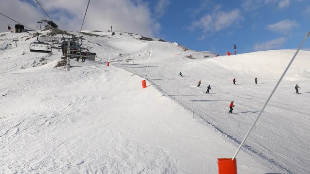Using ski lift in the Alps, people skiing on the slopes