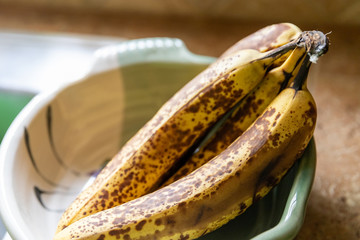 Close up of ripe bananas in decorative bowl on kitchen counter