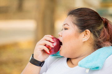 Overweight woman eating fresh apple after exercise