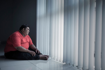 Pensive fat man looking out the window